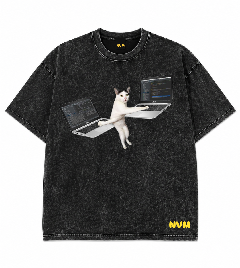 A black acid-wash short-sleeve t-shirt shown from both front and back. The front features a graphic of a white cat sitting at a laptop, and the back is solid black with a small yellow 'NVM' logo near the bottom hem.
