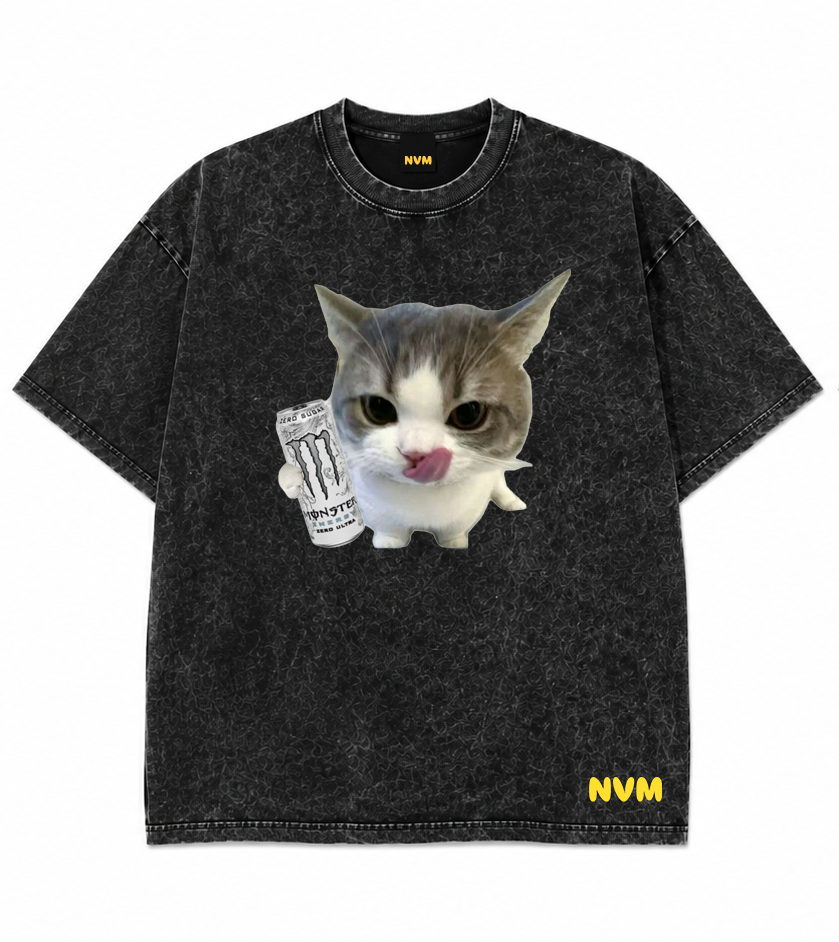 Front and back views of a black acid-wash t-shirt. The front features a graphic of a cat holding a mug with the text 'IT'S NOT A TEA TIME', and the back is plain black with a small yellow 'NVM' logo near the bottom hem.