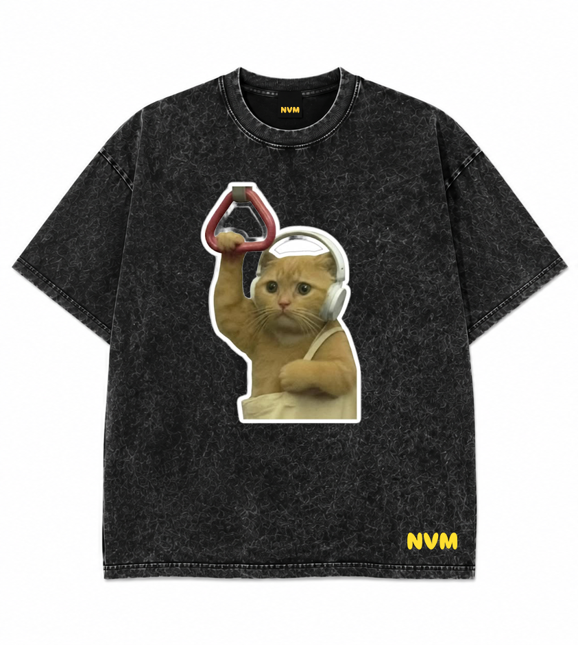 A black acid-wash t-shirt shown from both the front and back. The front features a graphic of a cat wearing headphones and holding a red object, with 'NVM' printed in yellow on the bottom right.