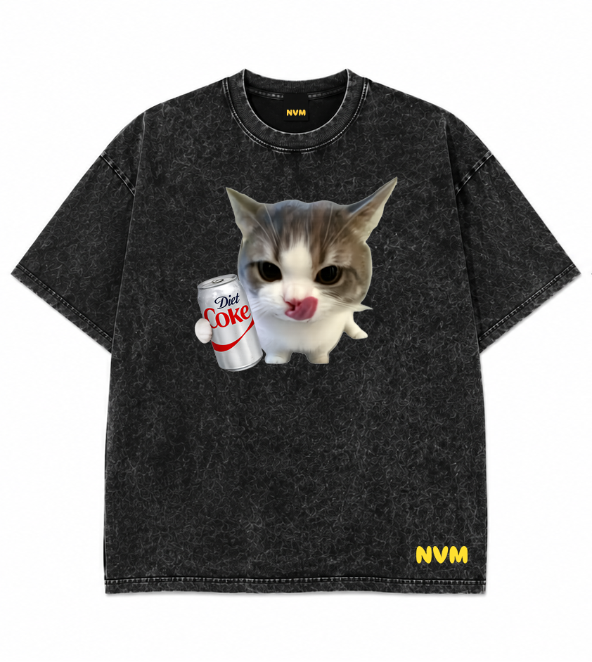 Front and back views of a washed black short-sleeve t-shirt. The front features a graphic of a cat holding a cup with the text 'I'M OKAY' and a yellow 'NVM' logo near the bottom hem.