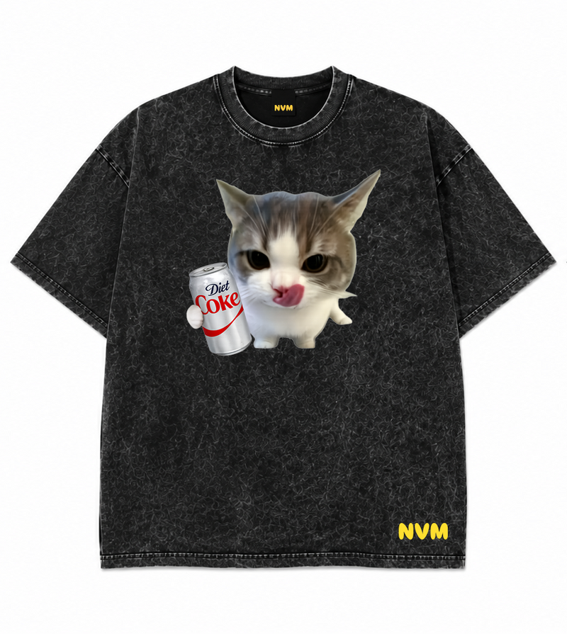 Front and back views of a washed black short-sleeve t-shirt. The front features a graphic of a cat holding a cup with the text 'I'M OKAY' and a yellow 'NVM' logo near the bottom hem.