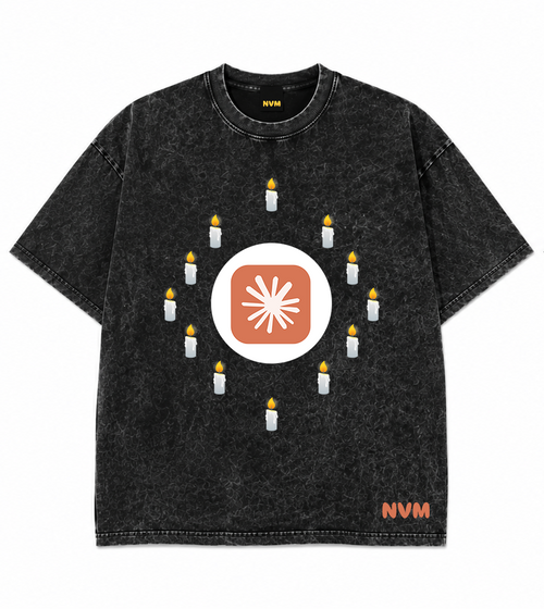 Front and back views of a black acid-wash t-shirt. The front features a circular graphic with candles surrounding a central sunburst logo, and 'NVM' printed in orange near the bottom hem.